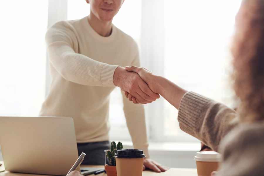 two adults shaking hands over a table