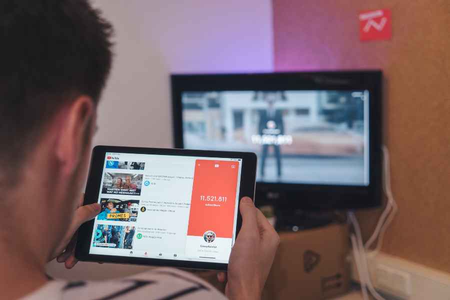 man watching an ipad in front of a computer