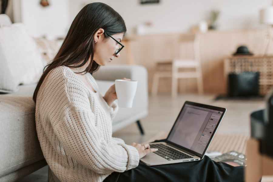 woman drinking a beverage and using a laptop