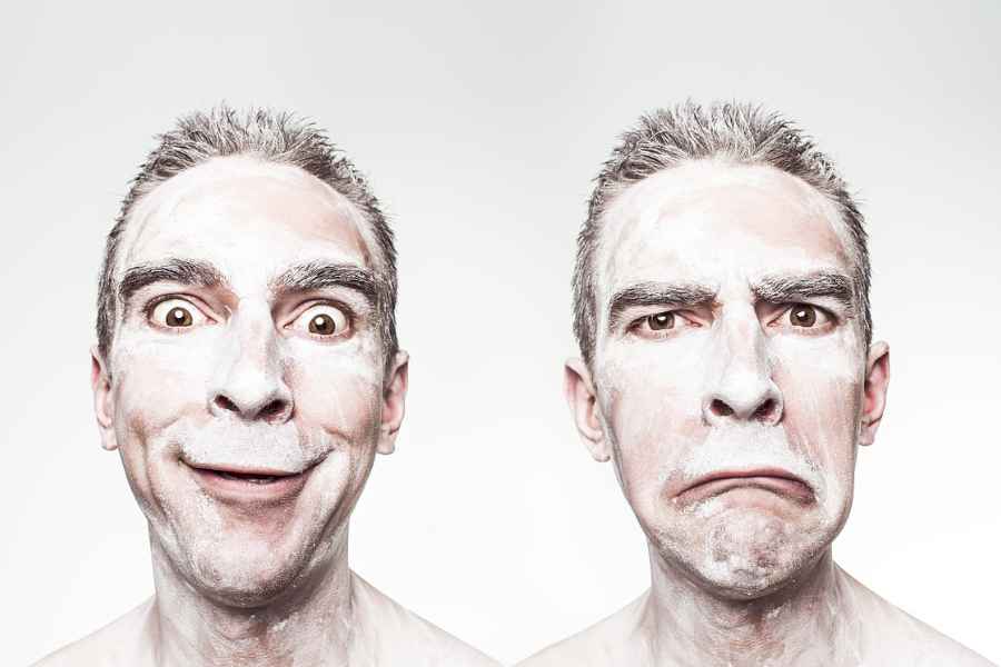 man with face painted white smiling, then frowning